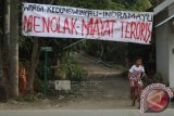 Warga melintas di bawah spanduk penolakan jenasah teroris di desa Kedungwungu, Krangkeng, Indramayu, Jawa Barat, Minggu (17/1). Sebagian warga desa tersebut menolak jenasah teroris Ahmad Muazan untuk dimakamkan di desa mereka. ANTARA FOTO/Dedhez Anggara/wdy/16.