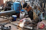 Seorang montir, I Wayan Sumardana alias Tawan memperbaiki alat sepeda motor pelanggan dengan lengan robot buatannya di bengkel kerjanya di Desa Nyuh Tebel, Karangasem, Bali, Kamis (21/1).  Pria tamatan SMK tersebut merancang lengan robot dari barang bekas dengan pengendali elektronik dan mekanik untuk membantu gerak lengan kirinya yang mengalami kelumpuhan sejak enam bulan lalu. ANTARA FOTO/Nyoman Budhiana/i018/2016.