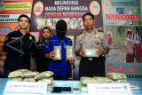 Petugas kepolisian bersama kurir pembawa ganja berinisial ZM (tengah) memperlihatkan barang bukti ganja saat gelar ungkap kasus di Mako Direktorat Reserse Narkoba Polda Kalbar, Rabu (20/1). Ditresnarkoba Polda Kalbar berhasil mengungkap pengiriman narkoba jenis ganja kering asal Aceh seberat 8,9 kilogram yang dilakukan oleh kurir berinisial ZF dan dikendalikan oleh seorang napi penghuni Lembaga Pemasyarakatan Kelas IIA Pontianak berinisial M. ANTARA FOTO/Jessica Helena Wuysang/16