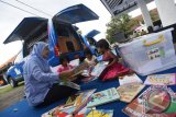 Petugas mendampingi sejumlah anak eks anggota Gerakan Fajar Nusantara (Gafatar) membaca buku di perpustakaan keliling di penampungan Asrama Transito Jawa Timur, Surabaya, Jawa Timur, Senin (25/1). Guna mendukung pembinaan anak-anak eks Gafatar, Pemprov Jawa Timur menyediakan sejumlah fasilitas seperti perpustakaan keliling dan mobil keliling internet. Antara Jatim/Zabur Karuru/16 