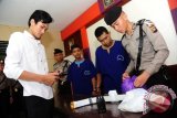 Tersangka polisi gadungan, Te (dua kanan) didampingi rekannya Le (tiga kanan) menyaksikan petugas kepolisian memperlihatkan barang bukti saat rilis kasus di Mapolsek Pontianak Selatan, Kalbar, Senin (15/2). Te yang dibekuk bersama rekannya, Le karena menganiaya juru parkir di Jalan Perdana Pontianak, Rudi Alfian pada Sabtu (13/2) malam dan mengaku bahwa dirinya anggota Provost tersebut, mengaku baru sekitar dua bulan memiliki atribut Provost Polri yang dibelinya karena terobsesi ingin menjadi petugas kepolisian. ( Foto Jessica Helena Wuysang).
