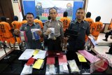 Kapolres Blitar AKBP Slamet Waloya (tengah) didampingi dua perwira polisi menunjukkan sejumlah barang bukti hasil pengungkapan kasus sindikat perjudian online dalam pres rilis di Mapolres Blitar, Jawa Timur, Kamis (18/2). Polres Blitar berhasil menangkap13 pelaku sindikat perjudian onlien beromzet puluhan juta, serta mengamankan alat bukti uang tunai dan berbagai peralatan elektronik yang diduga hasil kejahatan. Antara Jatim/Irfan Anshori/zk/16