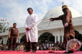 Algojo (kanan) mengeksekusi terpidana yang melanggar peraturan daerah (qanun) syariat islam (tengah) dengan menggunakan cambuk rotan di halaman Masjid Cot Mesjid, Kecamatan Lueng Bata, Banda Aceh, Aceh, Jumat (19/2). Pengadilan Mahkamah Syariah Kota Banda Aceh menvonis hukuman cambuk 5- 8 kali terhadap 7 warga yang terbukti melanggar Qanun nomor 13/2003 tentang maisir (perjudian). ANTARA FOTO/Irwansyah Putra/wdy/16.