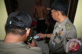 Petugas kepolisian dari Polresta Kediri memeriksa kartu identitas seorang tamu hotel saat Razia gabungan Kepolisian, TNI, dan Satpol PP di Kota Kediri, Jawa Timur, Jumat (19/2) malam. Razia guna menangkal perilaku menyimpang LGBT (Lesbian, Gay, Biseksual, Transgender) yang sedang marak di kota Kediri tersebut berhasil mengamankan 6 orang pasangan yang diduga melakukan tindakan asusila. Antara Jatim/Prasetia Fauzani/zk/16