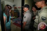 Petugas kepolisian dari Polresta Kediri memeriksa kartu identitas seorang tamu hotel saat Razia gabungan Kepolisian, TNI, dan Satpol PP di Kota Kediri, Jawa Timur, Jumat (19/2) malam. Razia guna menangkal perilaku menyimpang LGBT (Lesbian, Gay, Biseksual, Transgender) yang sedang marak di kota Kediri tersebut berhasil mengamankan 6 orang pasangan yang diduga melakukan tindakan asusila. Antara Jatim/Prasetia Fauzani/zk/16