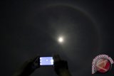 Seorang warga memotret fenomena Halo Bulan (Cincin Bulan) menggunakan handphone di Kota Blitar, Jawa Timur, Rabu (24/2) dinihari. Halo Bulan merupkan fenomena alam yang diakibatkan pembiasan cahaya bulan oleh uap air di atmosfer yang lembab, dimana bulan terlihat dikelilingi cincin dengan ukuran besar yang menyerupai pelangi. ANTARA FOTO/Irfan Anshori/16