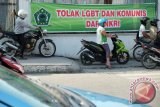 Pengendara sepeda motor berada didekat spanduk berisi penolakan terhadap kelompok Lesbian, Gay, Biseksual dan Transgender (LGBT) dan paham komunis, di kawasan Bundaran Majestik, Medan, Sumatera Utara, Rabu (2/3). Spanduk yang mengatasnamakan ISNU tersebut, sebagai bentuk penolan terhadap legilitas LGBT. ANTARA SUMUT/Irsan Mulyadi/16