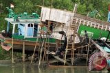 Pekerja mengecat kapal saat proses penyelesaian di galangan kapal bantaran sungai Krueng Aceh, di Banda Aceh, Sabtu (5/3). Beberapa pekerja menyatakan kesulitan memperoleh bahan baku kayu yang dibutuhkan untuk proses perbaikan maupun pembuatan kapal baru di daerah itu. ANTARA FOTO/Ampelsa/aww/16.