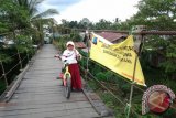 Seorang siswa melintasi jembatan gantung Pangkalan di Kecamatan Murung Pudak Kabupaten Tabalong yang dipasang tanda larangan untuk berenang di sekitar jembatan. Menyusul tewasnya siswa SD Negeri Agung saat terjun dari jembatan gantung ini dan bermain di sungai Tabalong.Foto:Antara/Herlina Lasmianti