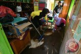 Sejumlah siswa dan guru SDN Petak membersihkan ruang perpustakaan dari lumpur usai dilanda banjir pada dini hari di Desa Petak, Kabupaten Nganjuk, Jawa Timur, Sabtu (12/3). Banjir yang dipicu oleh hujan lebat selama lima jam berturut-turut tersebut melanda sedikitnya 11 desa yang tersebar di 4 kecamatan dan mengakibatkan kegiatan belajar mengajar sejumlah sekolah terganggu. Antara Jatim/Prasetia Fauzani/zk/16