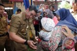 Gubernur Jambi Zumi Zola Zulkifli (kiri) menghibur balita yang akan diimunisasi usai Pencanangan Pekan Imunisasi Nasional (PIN) Polio Provinsi Jambi 2016 di Posyandu Kaswari, Kota Baru, Jambi, Selasa (8/3). Dinas Kesehatan Provinsi Jambi menyebutkan sebanyak 323.948 balita di daerah itu merupakan balita sasaran program PIN Polio 2016, dengan sasaran terbanyak berada di Kota Jambi dan Kabupaten Muarojambi. ANTARA FOTO/Wahdi Septiawan/ama/16.