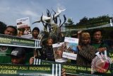 Sejumlah siswa SMP Muhammadiyah 1 Kapasan Surabaya membentangkan poster di depan patung Patung Suro dan Boyo di Kebun Binatang Surabaya saat aksi peringati Hari Dongeng Internasional, Surabaya, Jawa Timur, Jumat (18/3). Dalam aksi tersebut mereka menyerukan agar masyarakat tidak melupakan cerita dongeng Tana Air dan mendukung dongeng Indonesia sebagai kekayaan bangsa. ANTARA FOTO/Zabur Karuru/wdy/16