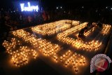 Warga menyalakan lilin bertuliskan angka 60 menjelang dimatikannya seluruh lampu listrik di monumen Simpang Lima Gumul, Kabupaten Kediri, Jawa Timur, Sabtu (19/3). Kegiatan mematikan lampu listrik dan mengganti dengan nyala lilin selama enam puluh menit tersebut sebagai kampanye penghematan energi guna menghindari pemanasan global. Antara Jatim/Prasetia Fauzani/zk/16