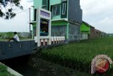 Warga berada didepan lahan pertanian yang berubah fungsi menjadi pemukiman di Jombang, Jawa Timur, Rabu (30/3). Tahun ini Pemkab Jombang menyiapkan Peraturan Daerah (Perda) tentang Penetapan lahan pertanian berkelanjutan, untuk menekan terjadinya alih fungsi lahan pertanian, sekaligus menjaga agar produksi pangan di wilayah Jombang tetap berjalan secara berkelanjutan. Antara Jatim/Syaiful Arif/zk/16