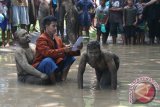 Sejumlah seniman dari sanggar Sastrajendra melakukan pertunjukan Teater di jalan yang banjir oleh air hujan di Desa Kaloran, Nganjuk, Jawa Timur, Minggu (3/4). Pertunjukan berjudul 'Baju Licin' tersebut merupakan kritik sosial terhadap pemimpin korup yang tidak memperdulikan penderitaan rakyat kecil. Antara Jatim/Prasetia Fauzani/zk/16