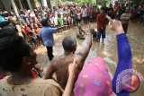 Sejumlah seniman dari sanggar Sastrajendra melakukan pertunjukan Teater di jalan yang banjir oleh air hujan di Desa Kaloran, Nganjuk, Jawa Timur, Minggu (3/4). Pertunjukan berjudul 'Baju Licin' tersebut merupakan kritik sosial terhadap pemimpin korup yang tidak memperdulikan penderitaan rakyat kecil. Antara Jatim/Prasetia Fauzani/zk/16