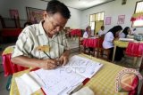 Eman Surya Yunus Bakir (43) mengikuti Ujian Nasional (UN) paket C di SMA Negeri 1 Kabila, Kabupaten Bone Bolango, Gorontalo, Rabu (6/4). Eman adalah seorang Kepala Desa Mootinelo, Kecamatan Bone Raya yang menjabat sejak tahun 2014 silam. (ANTARA FOTO/Adiwinata Solihin)