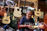 Seorang perajin menyelesaikan pembuatan gitar akustik di industri kerajinan gitar rumahan Le'John di Kota Denpasar, Bali, Senin (18/4). Gitar yang dijual dengan harga Rp1,5 juta - Rp7 juta tersebut telah dipasarkan ke sejumlah negara seperti Amerika, Prancis, Italia dan Australia. ANTARA FOTO/Fikri Yusuf/wdy/16