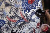 Perajin menorehkan malam pada bahan kain yang telah diberi motif batik tertentu di sentra batik tradisional di Desa Majan, Tulungagung, Jawa Timur, Selasa (19/4). Batik tulis majan dengan motif khas gadjah mada yang memiliki ciri lima unsur warna dalam satu kain dijual dengan harga di kisaran Rp500 ribu hingga Rp750 ribu per lembar. Antara Jatim/Destyan Sujarwoko/zk/16