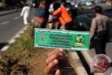 Seorang warga yang tergabung dalam Komunitas Bhakti Bersih memperlihatkan stiker bertema selamatkan bumi saat mengikuti aksi mencabut paku yang menancap pada pohon di sepanjang Jalan Andi Pangeran Pettarani, Makassar, Sulawesi Selatan, Jumat (22/4). Aksi mencabut paku pada sejumlah pohon tersebut dilaksanakan dalam rangka memperingati hari bumi, sekaligus sebagai bentuk upaya penyelamatan dan pemeliharaan pohon yang berfungsi sebagai penghijauan Kota Makassar. ANTARA FOTO/Abriawan Abhe/wdy/16