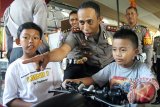 Kapolres Blitar AKBP Slamet Waloya (Dua kanan) mendampingi anak-anak bermain simulator kendaraan roda dua dalam penutupan Blitar Police Expo 2016 di Blitar, Jawa Timur, Minggu (24/4). Selain untuk mengenalkan berbagai peralatan khusus dan peralatan utama kepolisian, pameran yang digelar selama tiga hari tersebut juga bertujuan untuk mengkampanyekan gerakan nasional polisi sahabat anak. Antara/Irfan Anshori/zk/16