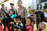 Kapolres Blitar AKBP Slamet Waloya (Kanan) menunjukkan cara kerja senjata pelontar gas air mata kepada anak-anak dalam penutupan Blitar Police Expo 2016 di Blitar, Jawa Timur, Minggu (24/4). Selain untuk mengenalkan berbagai peralatan khusus dan peralatan utama kepolisian, pameran yang digelar selama tiga hari tersebut juga bertujuan untuk mengkampanyekan gerakan nasional polisi sahabat anak. Antara Jatim/Irfan Anshori/zk/16