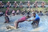 Wisatawan asing saling menjatuhkan di lumpur saat memperagakan seni beladiri Mepantigan di persawahan kawasan Batubulan, Gianyar, Bali, Minggu (24/4). Mepantigan merupakan seni beladiri asal Bali yang menggabungkan gerak beladiri, tarian tradisional, musik dan harmonisasi dengan hewan dan tumbuhan. ANTARA FOTO/Fikri Yusuf/aww/16.