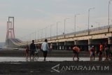 Sejumlah warga menikmati suasana sore hari di sekitar Jembatan Suramadu, Surabaya, Jawa Timur, Jumat (6/5). Jembatan dengan panjang sekitar 5,4 kilometer tersebut menjadi salah satu tempat wisata yang banyak dikunjungi warga untuk mengisi hari libur. Antara Jatim/Moch Asim/zk/16