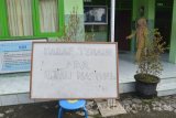 Seorang guru melintas di dekat papan peringatan ada Ujian Nasional (UN) di halaman SMP Luar Biasa (SMPLB) Dharma Wanita, Kota Madiun, Jawa Timur, Senin (9/5). Pelaksanaan UN tingkat SMP di sekolah tersebut diikuti dua orang siswa tuna rungu wicara. Antara Jatim/Foto/Siswowidodo/zk/16