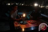 Warga menggunakan penerangan lilin makan kue dan minuman saat terjadi pemadaman listrik di salah satu warung kopi, Kota Banda Aceh, Selasa (10/5) malam. Pemberlakuan pemadaman listrik secara bergilir selama 4 jam hingga 6 jam dalam sehari yang terjadi sejak beberapa bulan terakhir itu mengganggu sejumlah usaha kecil rumah tangga termasuk ribuan warung kopi gelap dan sepi pengunjung. ANTARA FOTO/Ampelsa/foc/16.