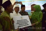 Menteri Sosial Khofifah Indar Parawansa (kanan) menyerahkan bantuan sosial kepada Ketua Majelis Pengasuh Ponpes Bahrul Ulum KH Hasib Wahab (dua kiri) di Jombang, Jawa Timur, Minggu (15/5). Dalam kesempatan itu Mensos menyerahkan santunan untuk anak yatim Ponpes Bahrul Ulum sebesar Rp 60 juta. Antara Jatim/Syaiful Arif/zk/16