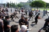 Sejumlah anggota polisi dan Satpol PP Jember mengejar mahasiswa yang berhamburan, usai berunjuk rasa di Kantor Pemkab Jember, Jawa Timur, Senin (23/5). Puluhan aktivis PMII Jember berdemonstrasi menolak tambang emas di Kecamatan Silo dan demo berakhir ricuh hingga menyebabkan pintu gerbang Kantor Pemkab Jember roboh. Antarajatim/Zumrotun Solichah/zk/16