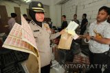 Polisi menunjukkan lembaran pita cukai saat penggrebekan gudang minuman keras (miras) impor di Surabaya, Jawa Timur, Rabu (1/6). Dalam penggrebekan tersebut Polrestabes Surabaya menyita ratusan botol miras impor yang diduga ilegal serta ratusan pita cukai yang selanjutnya akan dilakukan pemeriksaan lebih dalam. Antara Jatim/Didik Suhartono/zk/16