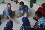 Mahasiswa dari Kansas University Amerika Serikat, Alex Doak (kiri) dan Bret John Ton (kedua kiri) bermain bola bekel di teras SMPN 2 Kota Madiun, Jawa Timur, Kamis (2/6). Sebanyak enam mahasiswa asal Kansas University Amerika serikat bertukar pengetahuan permainan tradisional Jawa dengan game Amerika Serikat, saat mengunjungi SMPN 2 dalam program Java Journey (petualangan di Jawa). Antara Jatim/Foto/Siswowidodo/zk/16