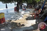 Seorang wisatawan membaca buku saat terjadi gelombang pasang di Pantai Kuta, Bali, Senin (6/6). Badan Penyelamat Wisata Tirta (Balawista) Pantai Kuta menutup sementara aktifitas wisata air di sepanjang pantai tersebut karena membahayakan. ANTARA FOTO/Nyoman Budhiana/i018/2016.