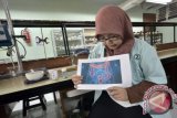 Mahasiswi Jurusan Farmasi Universitas Hasanuddin, Qonita Kurnia Anjani, menjelaskan manfaat kombinasi bakteri Laktobacillus Casei dan ekstrak kulit rambutan yang berguna untuk menjaga kesehatan usus dan mencegah kanker kolorektal (usus besar), Makassar, Sulawesi Selatan, Senin (6/6). Terinspirasi dari banyaknya limbah kulit rambutan, Qonita dan rekannya membuat inovasi yang kemudian di formulasikan dalam bentuk mikrokapsul. Produk tersebut berhasil meraih medali emas dalam kompetisi 8th Europan Exhibition of Creativity and Innovation (EUROINVENT) 2016 pada Mei 2016 lalu di Lasi Romania. ANTARA FOTO/Dewi Fajriani/wdy/16.