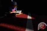 Seorang anak kecil membaca kitab suci Al Quran di Masjid Raya Al Mashun, Medan, Sumatera Utara, Minggu (12/6). Selama bulan suci Ramadan, umat muslim terus berupaya meningkatkan ibadah, dengan cara memperbanyak amalan-amalan yang disunahkan. ANTARA SUMUT/Septianda Perdana/16