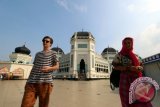 Warganegara asing beraktivitas di halaman Masjid Raya Medan atau Masjid Raya al-Mashun, di Medan, Sumatera Utara, Minggu (12/6). Obyek sejarah kebanggaan warga Medan dan Melayu yang dibangun oleh Kesultanan Deli pada tahun 1906 tersebut dirancang oleh arsitek asal Belanda dengan menggunakan gaya arsitektur perpaduan Timur Tengah, India dan Eropa menjadi pusat kegiatan ibadah saat bulan Ramadan. ANTARA SUMUT/Septianda Perdana/16