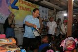 Menteri Koordinator Maritim dan Sumber Daya, Rizal Ramli (kedua kiri) didampingi Gubernur Sumatera Utara T Erry Nuradi (ketiga kiri) meminta seorang anak membaca buku ketika mengunjungi Perpustakaan Terapung Kampung Nelayan Belawan, di Medan, Sumatera Utara, Jumat (17/6). Kunjungan Menko Maritim dan Sumber Daya ke lokasi tersebut, dalam rangka memberikan bantuan fasilitas perpustakaan. ANTARA SUMUT/Irsan Mulyadi/16