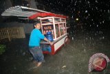 Pedagang sate melintasi banjir yang menggenangi jalan Kampung Nias, Padang, Sumatera Barat, Kamis (16/6/2016). Hujan lebat sejak Kamis sore membuat banjir menggenangi pemukiman dan ruas jalan di kota tersebut. (ANTARA FOTO/Iggoy el Fitra)