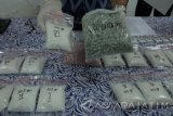 Petugas Badan Narkotika Nasional Provinsi Jawa Timur menunjukkan barang bukti Sabu dan  ekstasi saat ungkap kasus peredaran narkoba di Kantor Badan Narkotika Nasional Provinsi (BNNP) Jawa Timur, Surabaya, Jawa Timur, Jumat (17/6). BNNP Jatim menangkap dua tersangka berinisial  M T (33) dan M B L (29) atas kasus dugaan mengedarkan narkoba dan mengamankan barang bukti Sabu seberat 2 kilogram serta pil ekstasi sebanyak 3.000 butir yang diduga merupakan pesanan salah satu narapidana Lapas Sidoarjo berinisial B. Antara Jatim/Didik Suhartono/zk/16