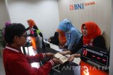 Karyawan bank melayani nasabah di Bank BNI Syariah, Malang, Jawa Timur, Kamis (23/6). BNI Syariah mencatat, pembiayaan rumah per Mei 2016 hanya mencapai Rp500 miliar atau turun sekitar 20 persen dari angka pembiayaan rumah per Mei 2015 yang mencapai Rp700 miliar. Antara Jatim/Ari Bowo Sucipto/zk/16.