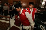 Terdakwa kasus pembunuhan aktifis tambang pasir Lumajang Salim Kancil dan penganiayaan Tosan, Kepala Desa Selok Awar-Awar (non aktif) Hariyono (kanan) dan Mad Dasir (kedua kanan) memasuki ruang sidang di Pengadilan Negeri Surabaya, Jawa Timur, Kamis (23/6). Dalam sidang dengan agenda pembacaan putusan (vonis) majelis hakim menjatuhkan hukuman 20 tahun penjara kepada kedua terdakwa. Antara Jatim/Didik Suhartono/zk/16