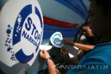 Dua orang petugas Badan Narkotika Nasional (BNN) menempelkan stiker bertuliskan 'Stop Narkoba' pada bus angkutan umum di terminal Pare, Kabupaten Kediri, Jawa Timur, Sabtu (25/6). Aksi penempelan stiker pada sejumlah angkutan umum tersebut merupakan upaya kampanye kepada masyarakat agar memerangi narkoba dan sekaligus sebagai rangkaian kegiatan memperingati Hari Narkotika Internasional. Antara Jatim/Prasetia Fauzani/zk/16