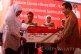 Menteri Sosial, Khofifah Indar Parawansa (kiri) menerima kartu kombo dari Wakil Direktur Bank BNI, Suprajarto (kanan) untuk diserahkan kepada warga penerima manfaat dalam peluncuran layanan e-Warung di Tunjungsekar, Malang, Jawa Timur, Senin (27/6). Layanan e-Warung Kelompok Usaha Bersama (KUBE)- Program Keluarga Harapan (PKH)-Koperasi Masyarakat Indonesia Sejahtera (KMIS) yang merupakan kerjasama Kementerian Sosial dengan Bank BNI tersebut  merupakan warung pertama dengan model transaksi non tunai yang dibentuk untuk menekan angka inflasi agar tidak melejit serta mengurangi angka kemiskinan melalui usaha bersama seiring dengan penyaluran dana bantuan sosial (bansos) non tunai. Antara Jatim/Ari Bowo Sucipto/zk/16