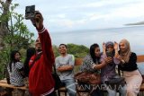 Sejumlah wisatawan berfoto di Puncak Sunrise Watu Dodol, Banyuwangi, Jawa Timur, Selasa (28/6). Puncak sunrise merupakan tempat wisata baru di Banyuwangi yang saat ini sering dikunjungi wisatawan untuk menikmati keindahan selat bali dan maskot gandrung Banyuwangi sambil menunggu saat berbuka puasa. Antara Jatim/ Budi Candra Setya/zk/16.