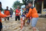 Sejumlah relawan membantu warga saat melewati lokasi banjir jalan pantura kraton, Pasuruan, Jawa Timur, Kamis (30/6). Banjir setinggi 1 meter tersebut terjadi akibat meluapnya Sungai Welang setelah diguyur hujan lebat sejak Rabu (29/6) malam sehingga membuat jalur pantura lumpuh. Antara Jatim/Umarul Faruq/zk/16
