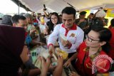 Menteri Pertanian Andi Amran (kedua kanan) melayani warga yang membeli minyak goreng murah di Surabaya, Jawa Timur, Senin (27/6). Kehadiran Mentan di Surabaya tersebut dalam rangka meluncurkan Toko Tani Indonesia. ANTARA FOTO/Didik Suhartono/wdy/16