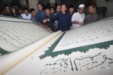 Menpora Imam Nahrawi (tengah) bersama jamaah pengajian mengamati Al-Quran berukuran 1x1,5 meter disela-sela sahur bersama di Kediaman Surabaya, Jawa Timur, Minggu (3/7). Sahur bersama yang diikuti sejumlah organisasi kepemudaan untuk mempererat tali silaturahmi yang mampu menciptakan dan meningkatkan suasana yang kondusif.  Antara Jatim/M Risyal Hidayat/zk/16