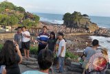 Sejumlah wisatawan domestik berfoto saat liburan di obyek wisata Tanah Lot, Tabanan, Bali, Jumat (8/7). Kunjungan wisatawan ke obyek wisata tersebut meningkat mencapai 16 ribu orang/hari dari biasanya rata-rata 10 ribu orang/hari karena liburan panjang Idul Fitri 1437 H. ANTARA FOTO/Nyoman Budhiana/i108/2016.